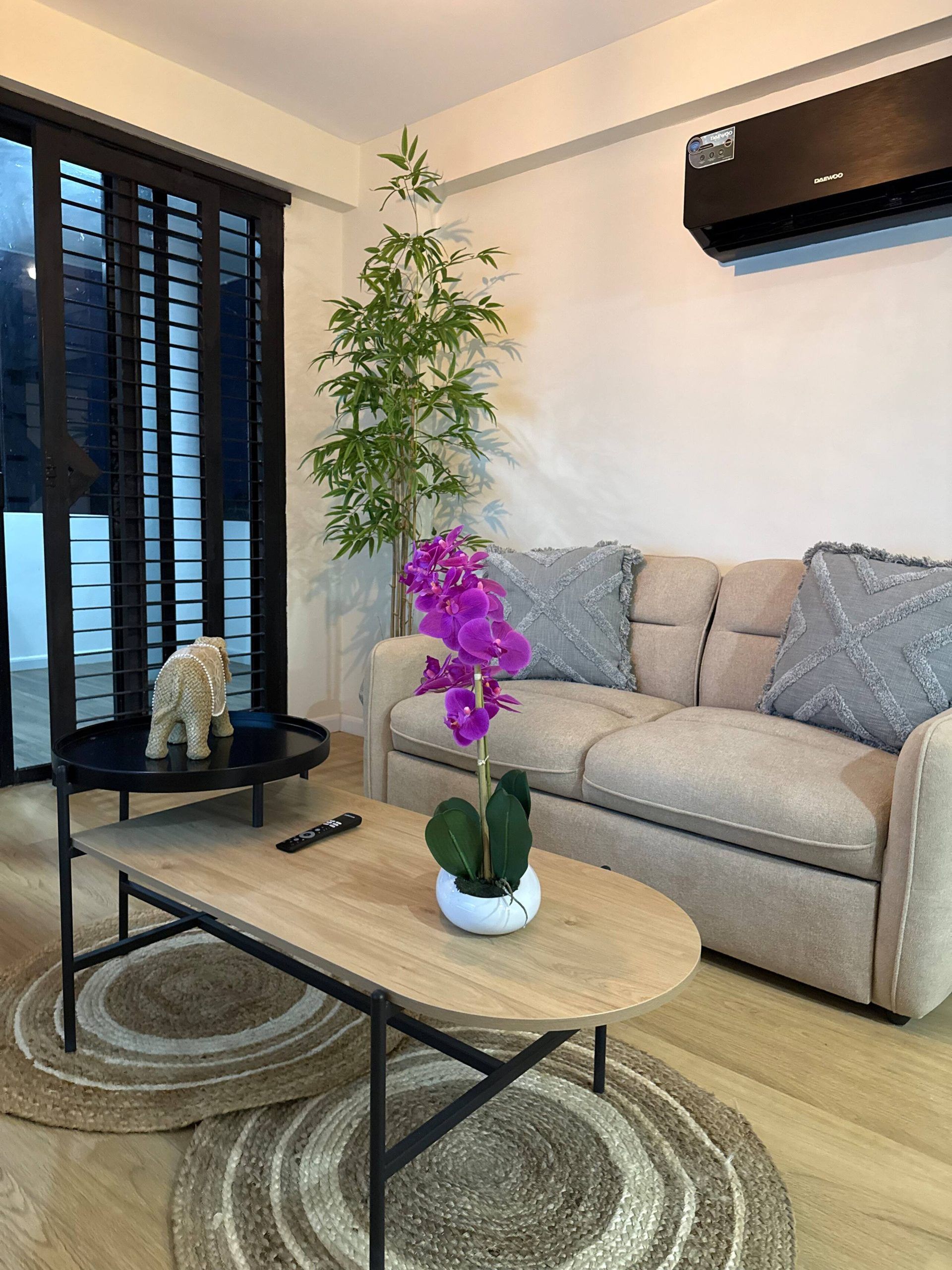 A modern living room with a sofa, a coffee table, a potted plant, and a decorative elephant figurine.