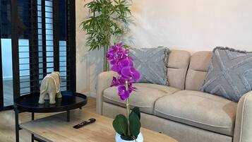 A modern living room with a sofa, a coffee table, a potted plant, and a decorative elephant figurine.