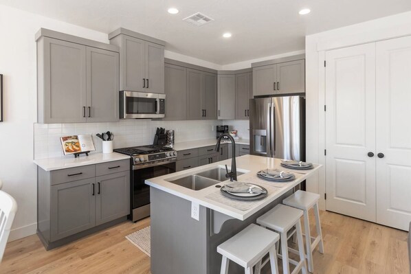 A modern kitchen with grey cabinets, stainless steel appliances, and a central island with stools. - Close to National and State Parks - Heated Pool, Hot Tub, Bunk Beds (Washington)