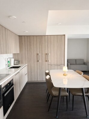 Cozinha moderna com área de refeições, equipada com forno embutido, micro-ondas e mesa com cadeiras.