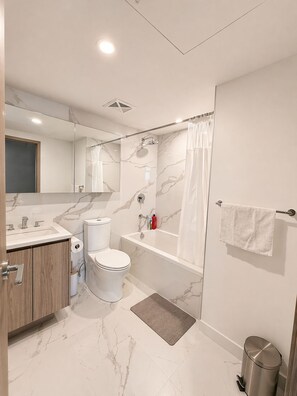 Ein modernes Badezimmer mit Toilette, Waschbecken, Badewanne und Dusche.