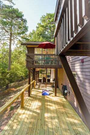Une terrasse en bois avec un espace salon abrité et un parasol rouge.