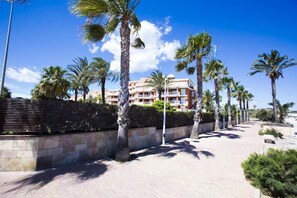 A pathway lined with palm trees leading to a building with balconies. - 176 Estrella de Mar, 6 (denia)
