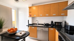 A modern kitchen with wooden cabinets, a dishwasher, a stove, and a sink. - 176 Estrella de Mar, 6 (denia)