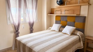 A bed with a striped bedspread, a headboard with a geometric pattern, and a nightstand with a drawer. - 176 Estrella de Mar, 6 (denia)