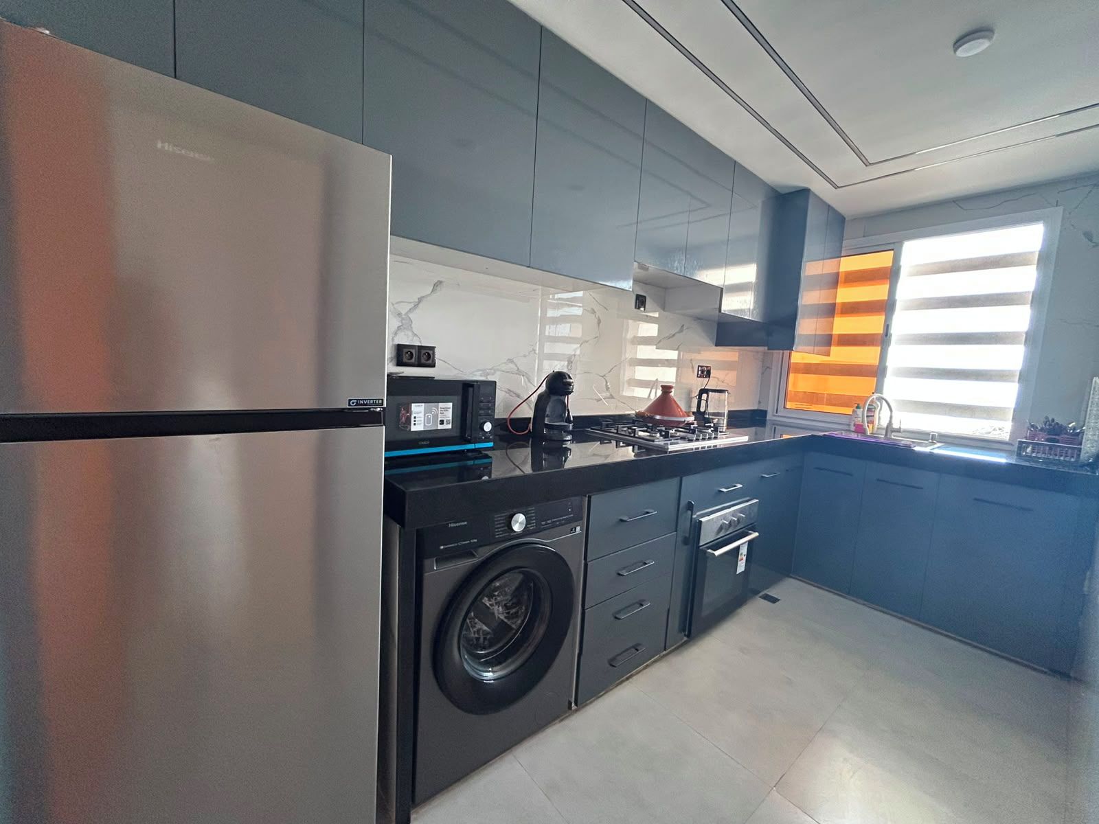 Una cocina moderna con un refrigerador de acero inoxidable, una lavadora y una estufa a gas.
