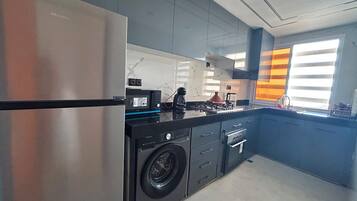 Una cocina moderna con un refrigerador de acero inoxidable, una lavadora y una estufa a gas.