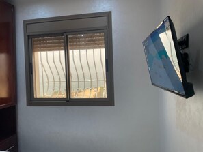 Habitació amb finestra i televisió penjada.