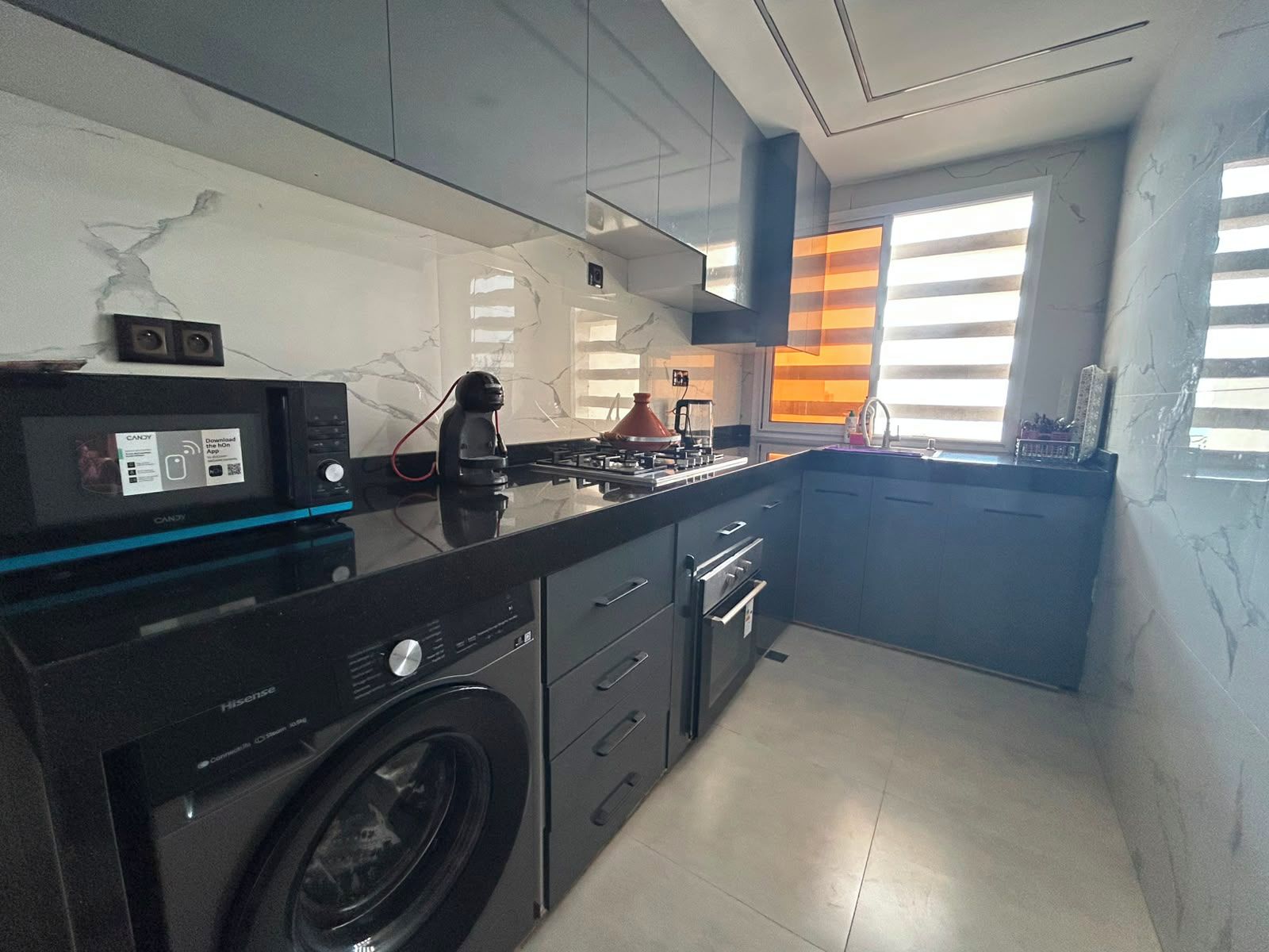 A modern kitchen with a washing machine, a microwave, and a stove.