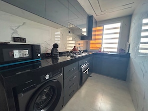 A modern kitchen with a washing machine, a microwave, and a stove. - Sea View Agadir (Agadir)