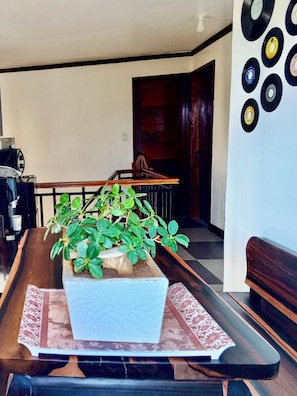 Una mesa de comedor con una planta en maceta, un banco y una pared decorada con discos de vinilo.