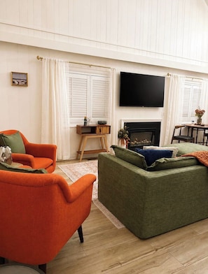 A living room with a fireplace, a television mounted on the wall, and two sofas. - 62 Newport Dr (Ocean Pines)