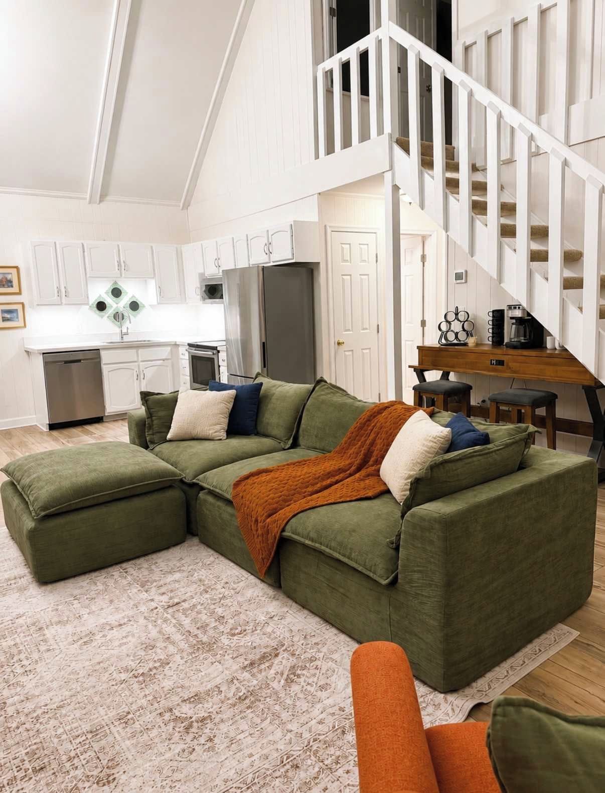 A modern living room with a sectional sofa, a coffee table, and a staircase leading to an upper level.