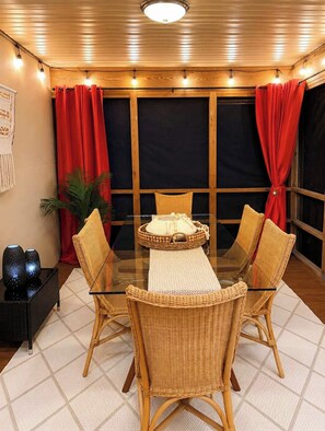A dining area with a glass table, wicker chairs, and red curtains. - 62 Newport Dr (Ocean Pines)