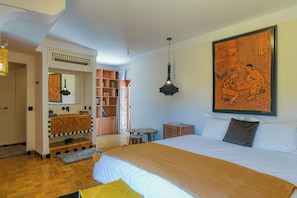 A hotel room with a large bed, a bathroom with a sink and mirror, a bookshelf, and a large artwork on the wall. - Asilah (Marrakech)