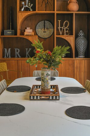 A dining table with a decorative centerpiece, surrounded by chairs with woven placemats. - Asilah (Marrakech)