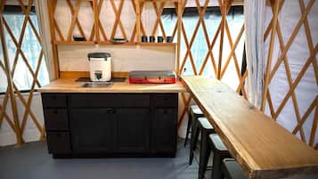 Een kleine keuken met een houten aanrecht, een spoelbak en een koffiezetapparaat.