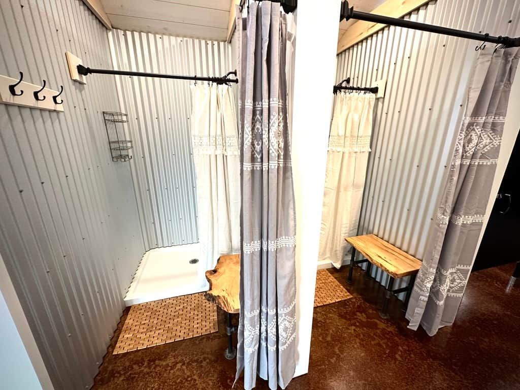 Une salle de bain avec un rideau de douche, un banc et un porte-serviettes.