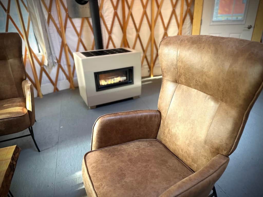 A room with a brown leather chair, a white heater, and a wooden lattice partition.