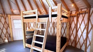 Una habitación con una litera de madera, una escalera y una puerta.