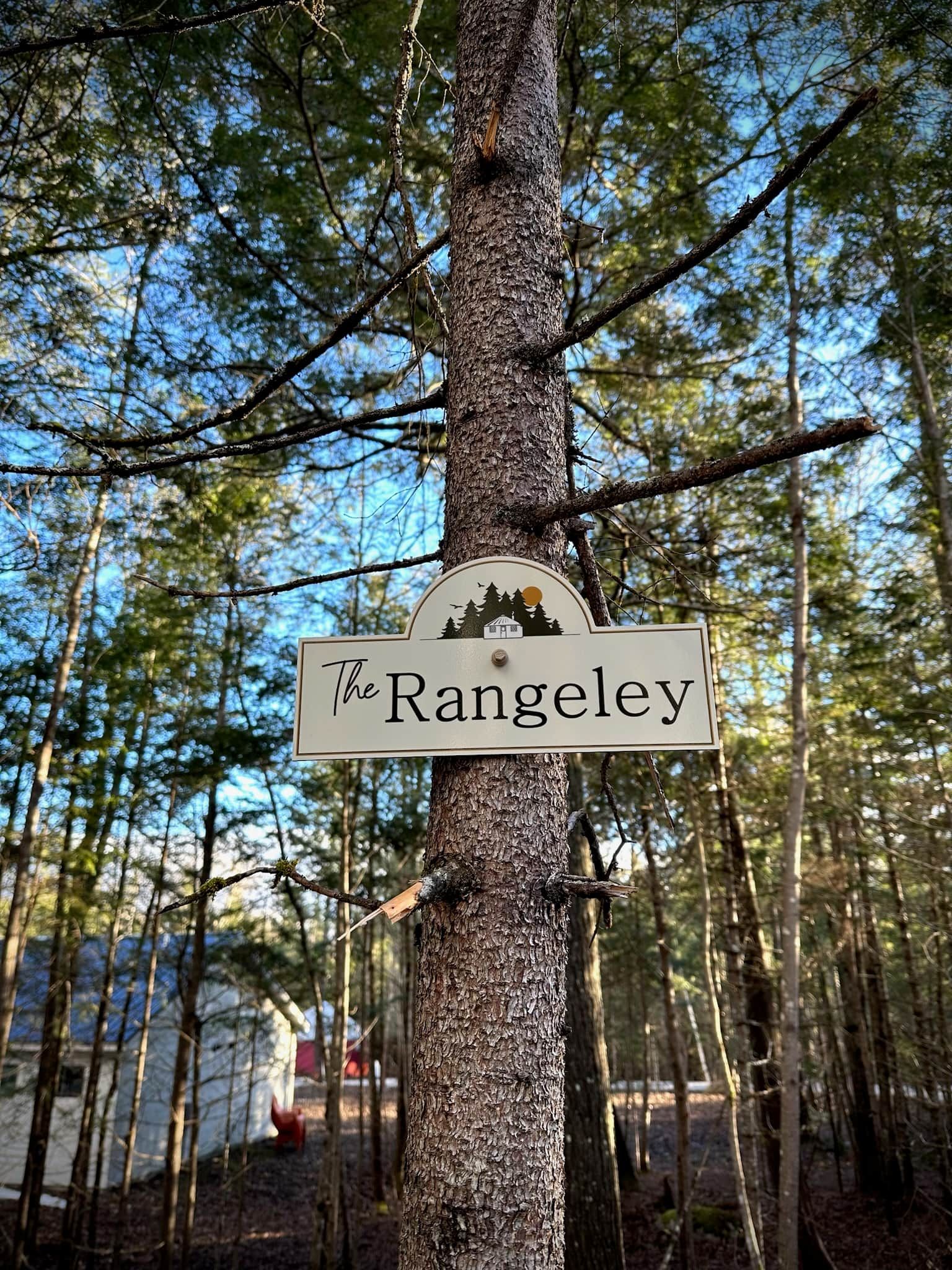 A sign on a tree labeled 'The Rangeley' with a depiction of a house and trees.