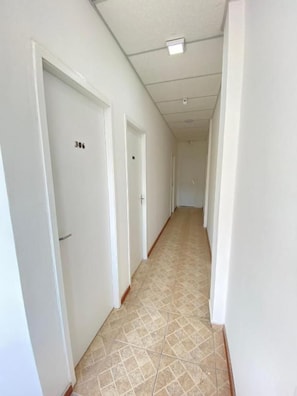 A corridor with white doors, each marked with a number. - Pousada Queiroz (Rio de Janeiro)