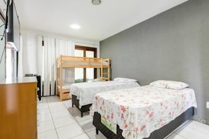 A room with bunk beds, a desk, and a window with curtains.
