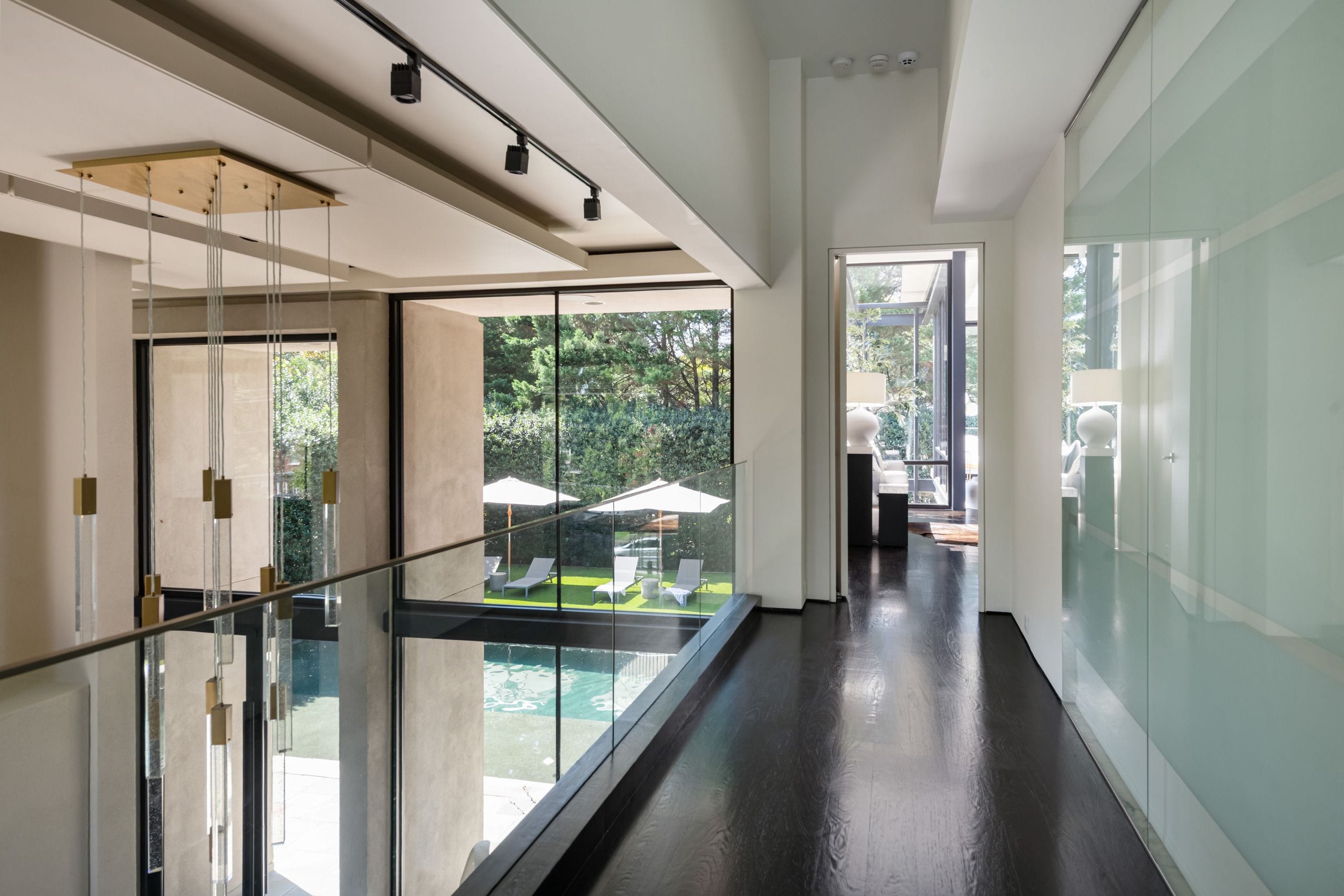 A modern interior with a glass railing overlooking a pool area.