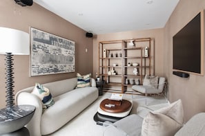 A modern living room with a sofa, coffee table, and a bookshelf. - Amani Manor (Atlanta)