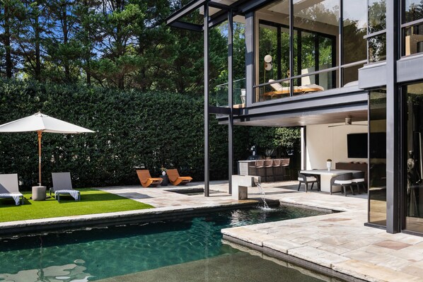 Une maison moderne dotée d’une piscine, d’un espace salon extérieur et d’un coin repas.