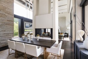 Un intérieur moderne avec une grande table à manger, des chaises blanches et une cheminée.