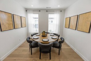 Une salle à manger avec une table ronde, six chaises et une plante en pot.