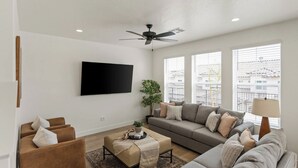 Ein modernes Wohnzimmer mit Flachbildfernseher, Deckenventilator, einer Sofagarnitur und einem Couchtisch.