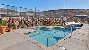 Ein Poolbereich mit Steinmauer, Liegestühlen und Blumentöpfen.