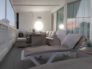 A balcony with a wicker sofa, a lounge chair, and a table with a lamp. - Boutique Atalaya Sea View (NEW, 34 five-star reviews on a well-known partner website) (COSTA ADEJE)