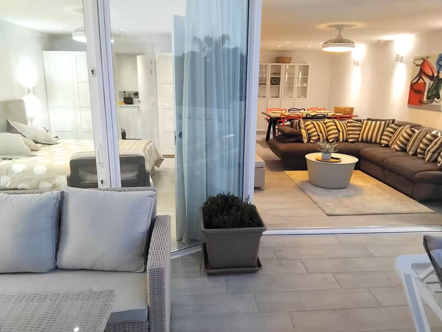 A modern living room with a sofa, a coffee table, and a dining area with chairs and a table.