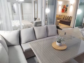 A modern living room with a sofa, a coffee table, and a view into the adjacent bedroom. - Boutique Atalaya Sea View (NEW, 34 five-star reviews on a well-known partner website) (COSTA ADEJE)