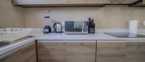 Una cocina con armarios de madera, un microondas, una licuadora y una tetera.