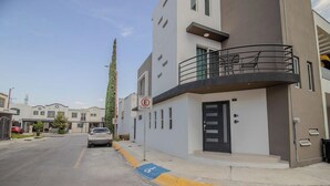 A modern building with a balcony, a no parking sign, and a blue handicapped parking space. - Comfortable King Loft in Apodaca - Ground Floor (Ciudad Apodaca)