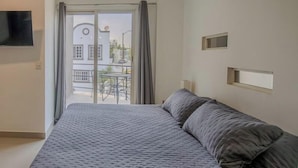 Ein Schlafzimmer mit einem Bett, einem an der Wand montierten Fernseher und Blick ins Freie.