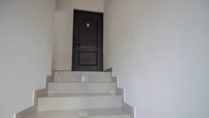 Eine Treppe führt zu einer dunklen Tür, auf der das Zeichen 'B' angebracht ist.