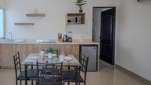 Eine moderne Küche mit einem Esstisch für vier Personen, einem Kühlschrank und einer kleinen Kücheninsel mit Spüle.