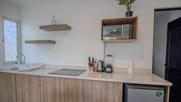 Eine moderne Küche mit Holzausstattung, einer integrierten Mikrowelle, einer Kaffeemaschine und einem Kühlschrank.