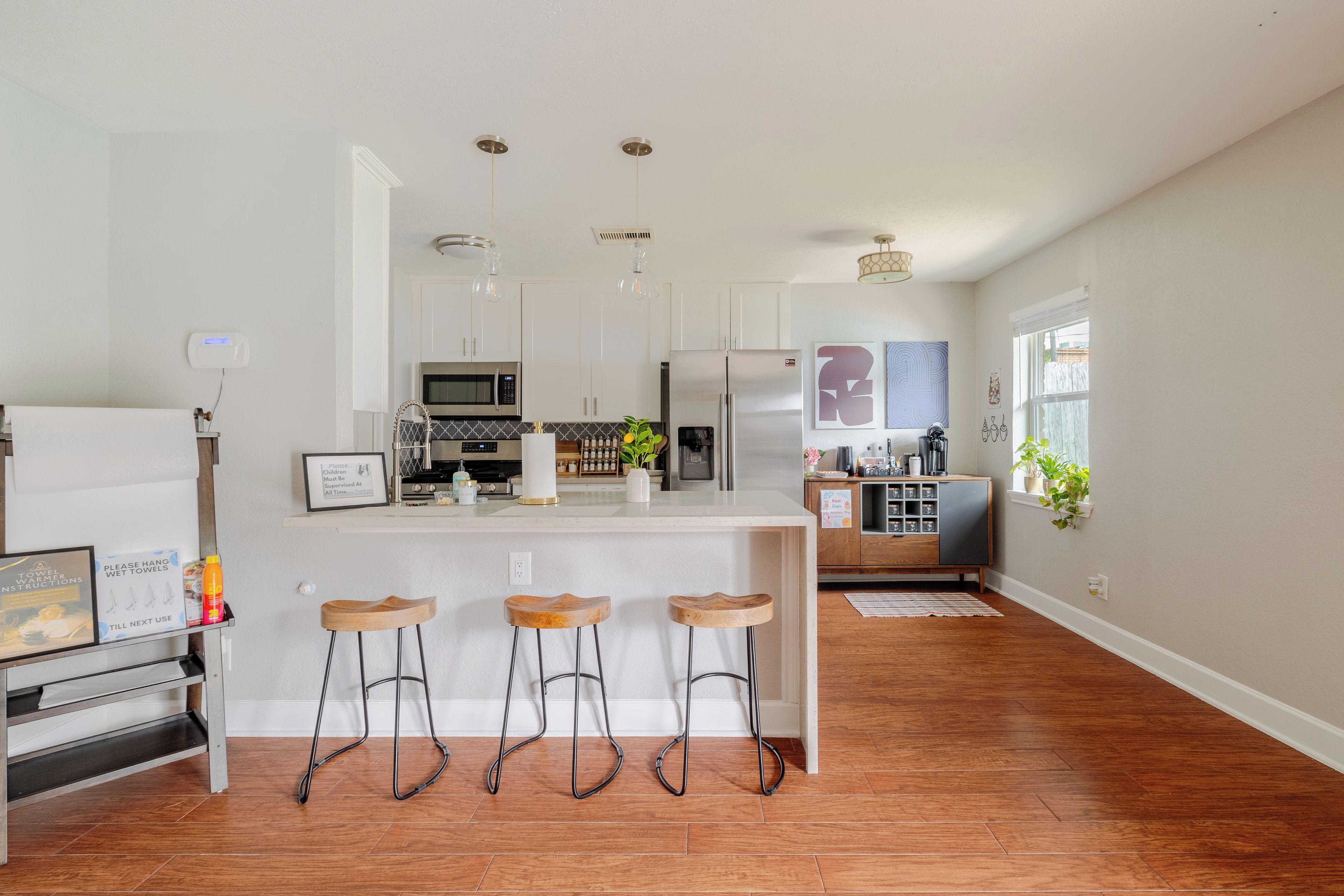 A modern kitchen with a central island, bar stools, and a dining area with a view.