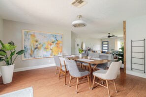 A dining area with a wooden table and chairs, a large abstract painting on the wall, and a potted plant. - Private Home with Jacuzzi and Large Deep Pool close to NRG/Galleria/Downtown (Houston)
