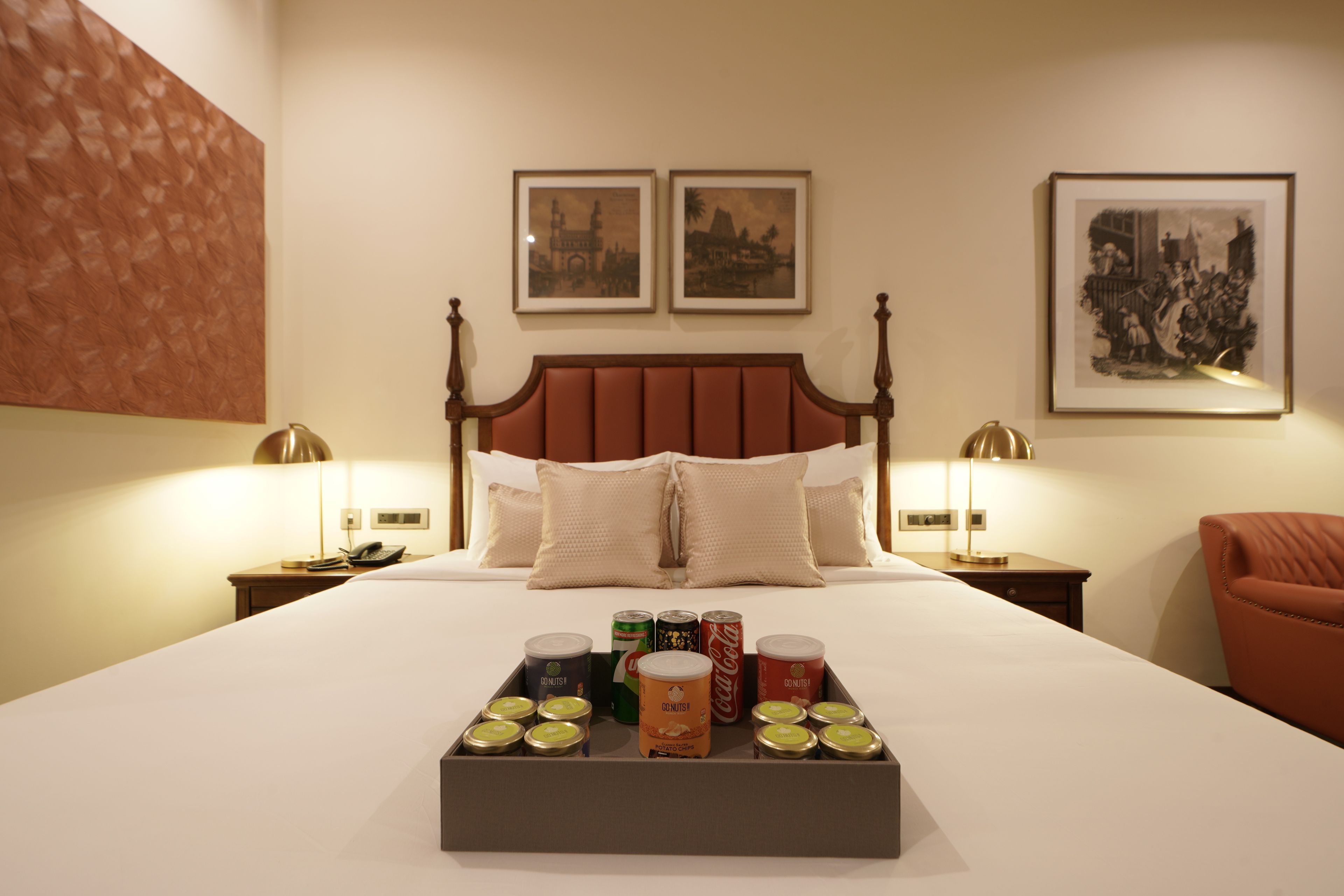 Habitación de hotel con cama con dosel, dos mesitas de noche con lámparas, una mesita con teléfono y una bandeja de aperitivos.