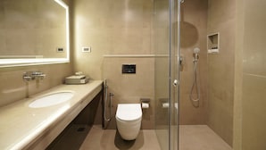 Un baño moderno con cabina de ducha de vidrio, inodoro y tocador con espejo.