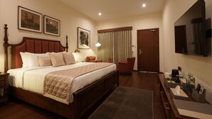 Habitación de hotel con una cama grande, un escritorio, una silla, un televisor de pantalla plana y un ventilador de techo.