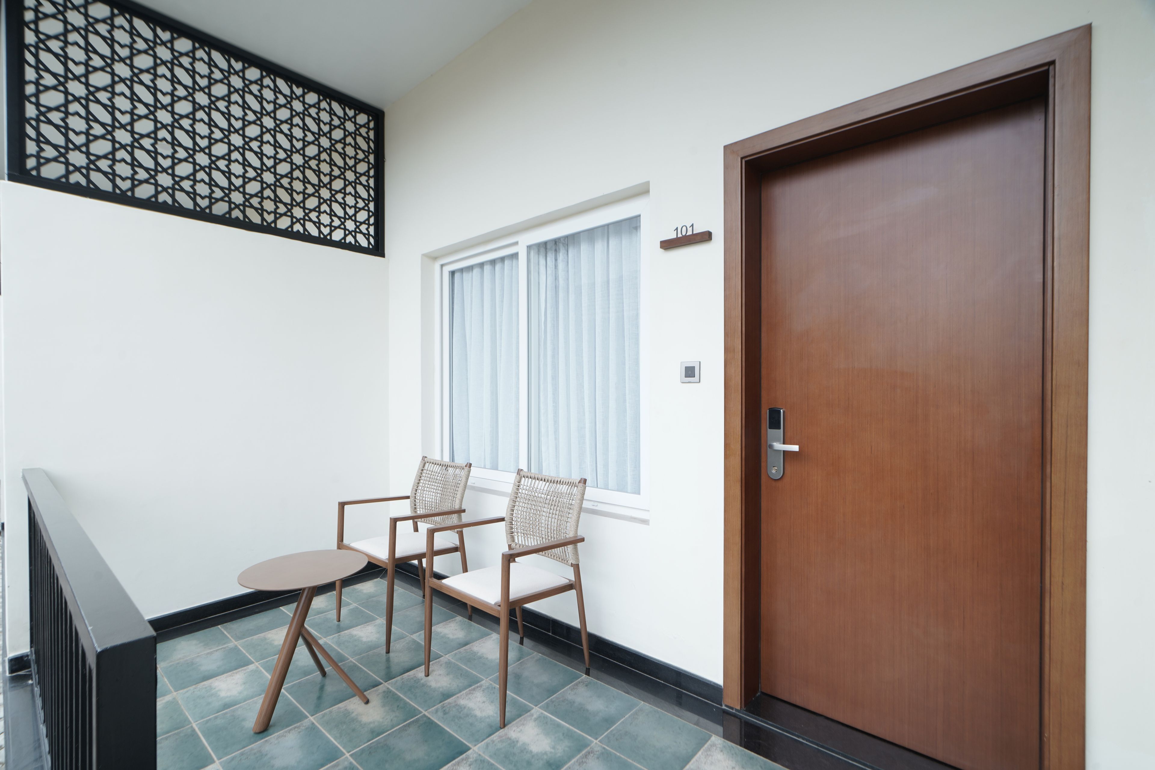 A room with a wooden door, a window with curtains, and two chairs.