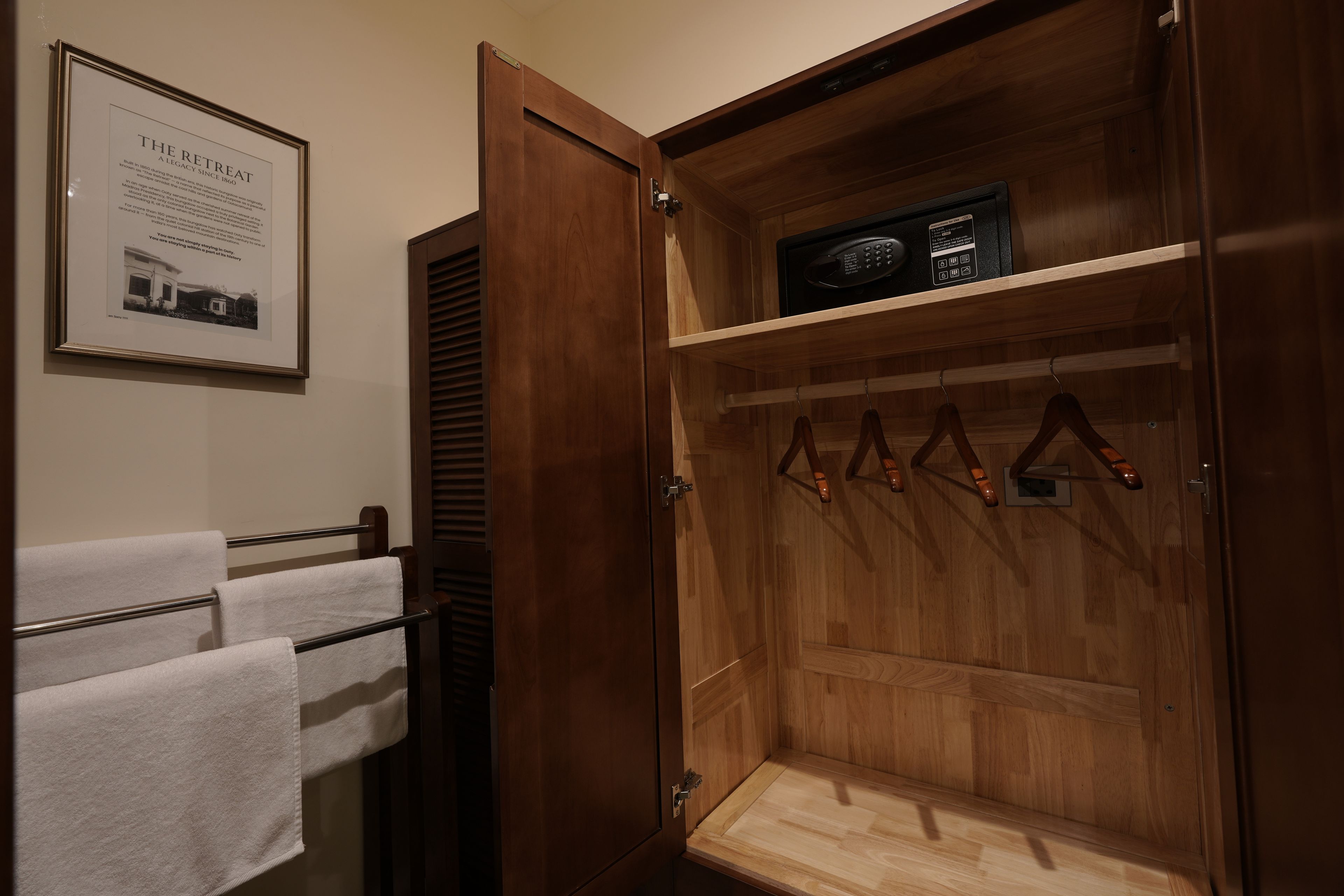 A wooden wardrobe with a built-in radio, a towel rack, and a framed historical plaque.